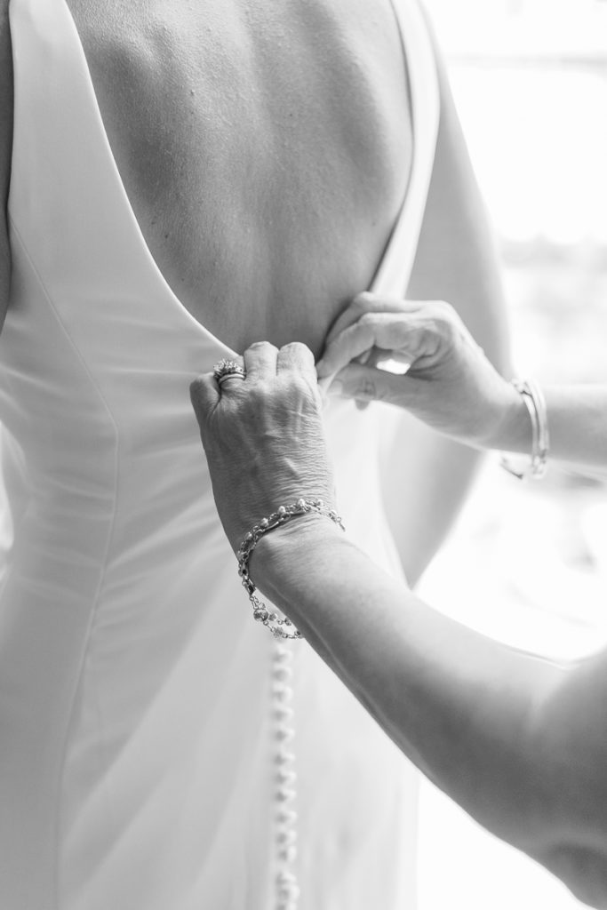 Mother of the bride zipping up her Watters wedding dress