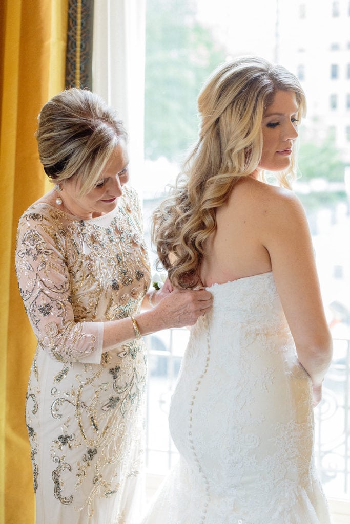 Mother of the bride helping bride into wedding dress