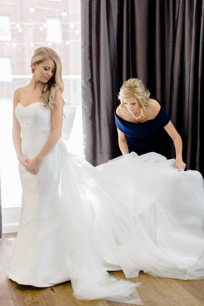 Mother of the bride fluffing bride's wedding gown captured by Lauren Renee