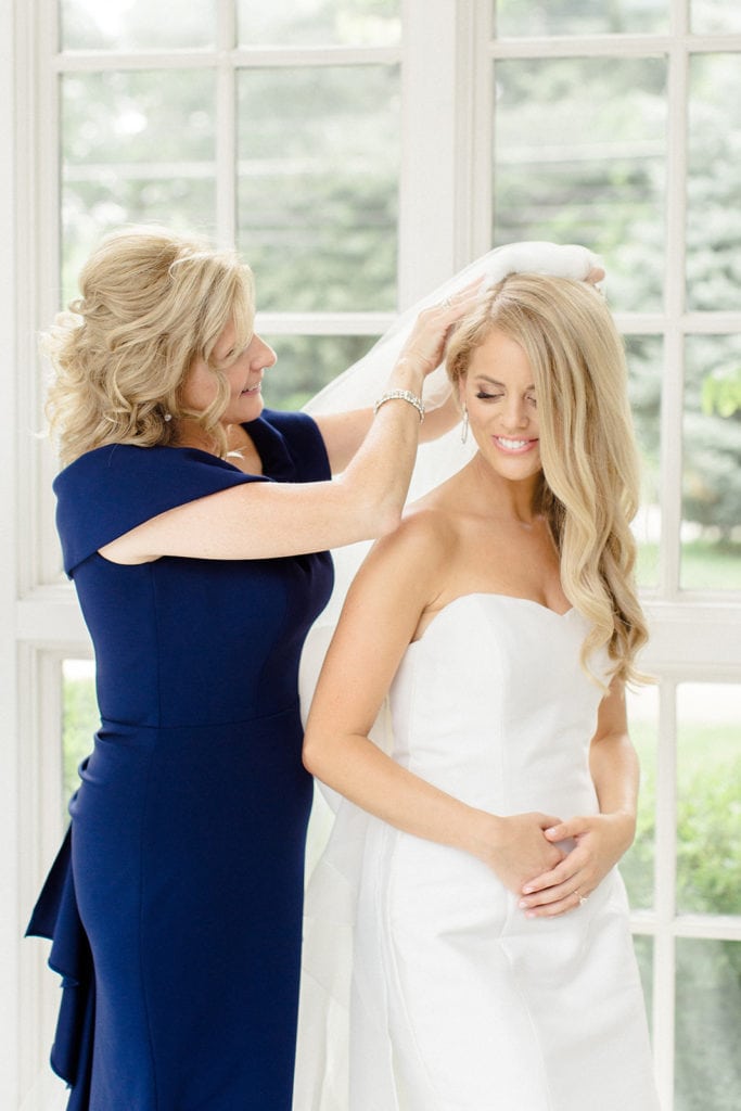 Mother of the bride placing wedding veil