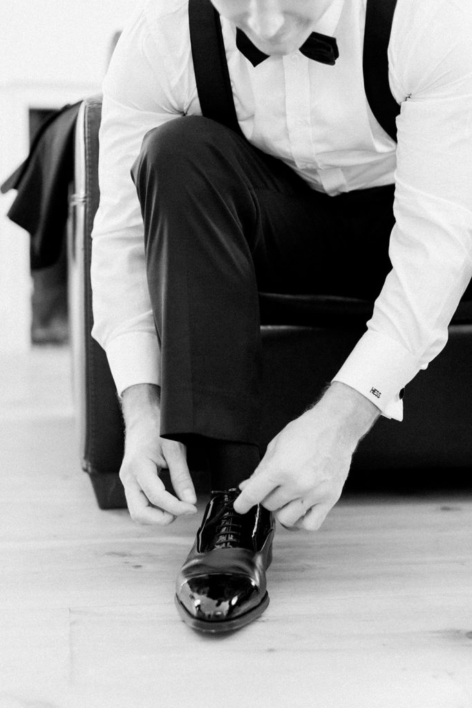 Groom tying wedding shoes