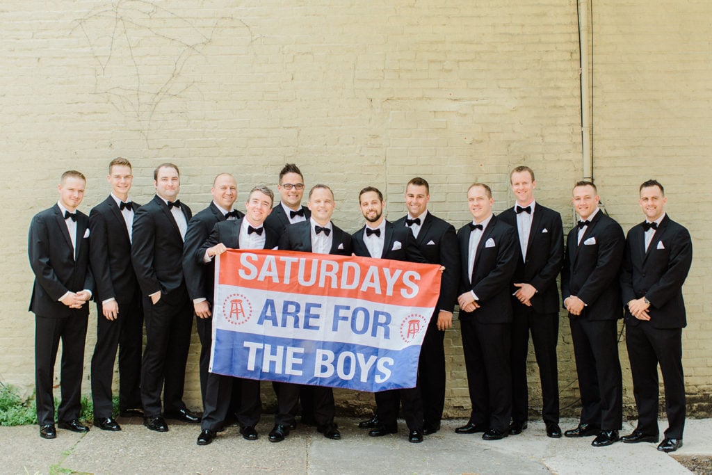 Groom and groomsmen posing with sign