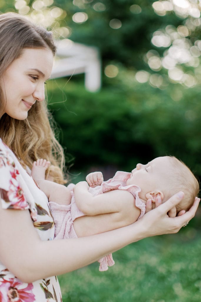 mother holding her newborn baby in her arms in mellon park: outdoor newborn session