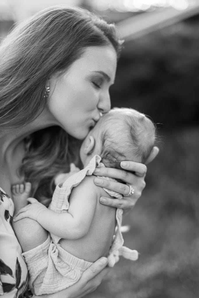 black and white image of mother kissing her newborn baby in an english garden: outdoor newborn session