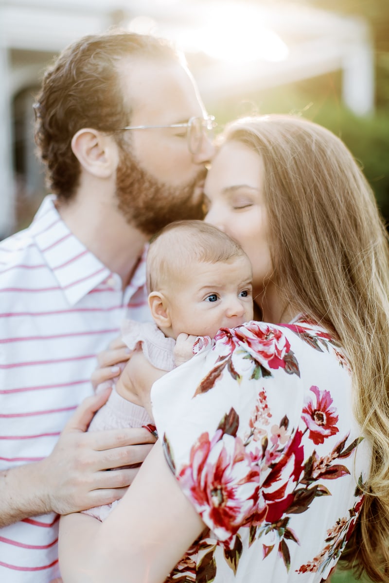 newborn baby being hugged and kiss by parents in their english garden: outdoor newborn session: outdoor newborn session