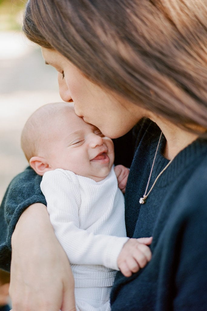 Mom kissing baby's forehead during family session