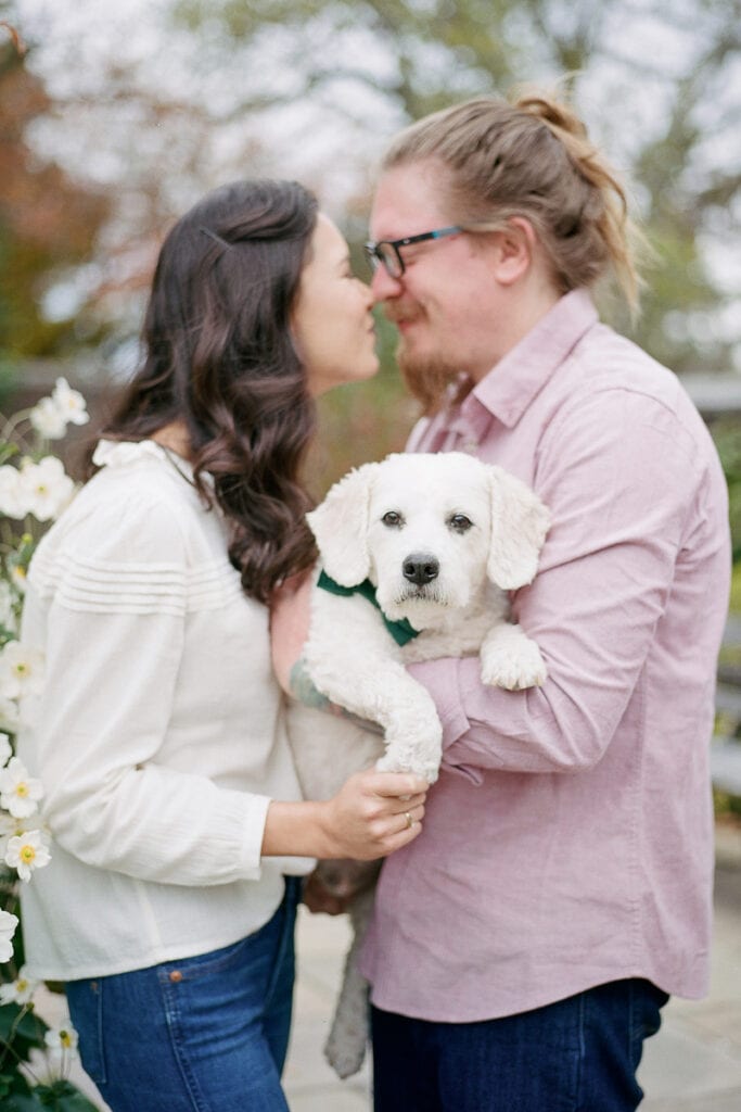 Couple holding their dog and exchanging eskimo kisses