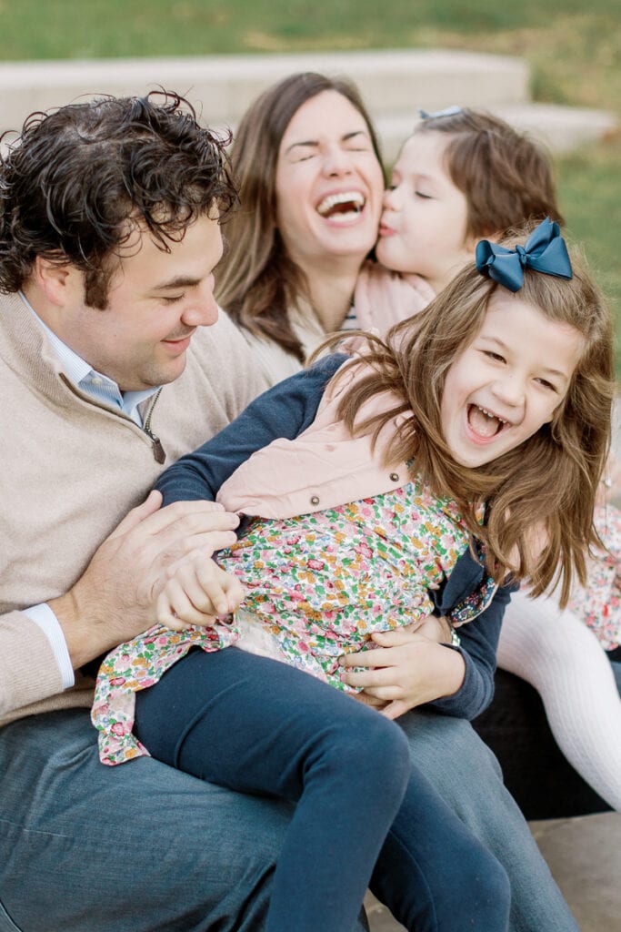 Mom and dad laughing with their two daughters