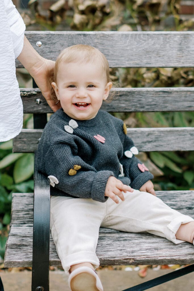 Baby boy sitting on a park bench smiling