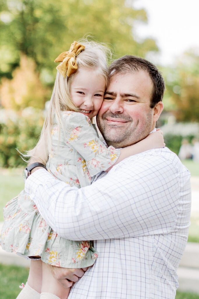 Little girl with a yellow bow hugging her dad