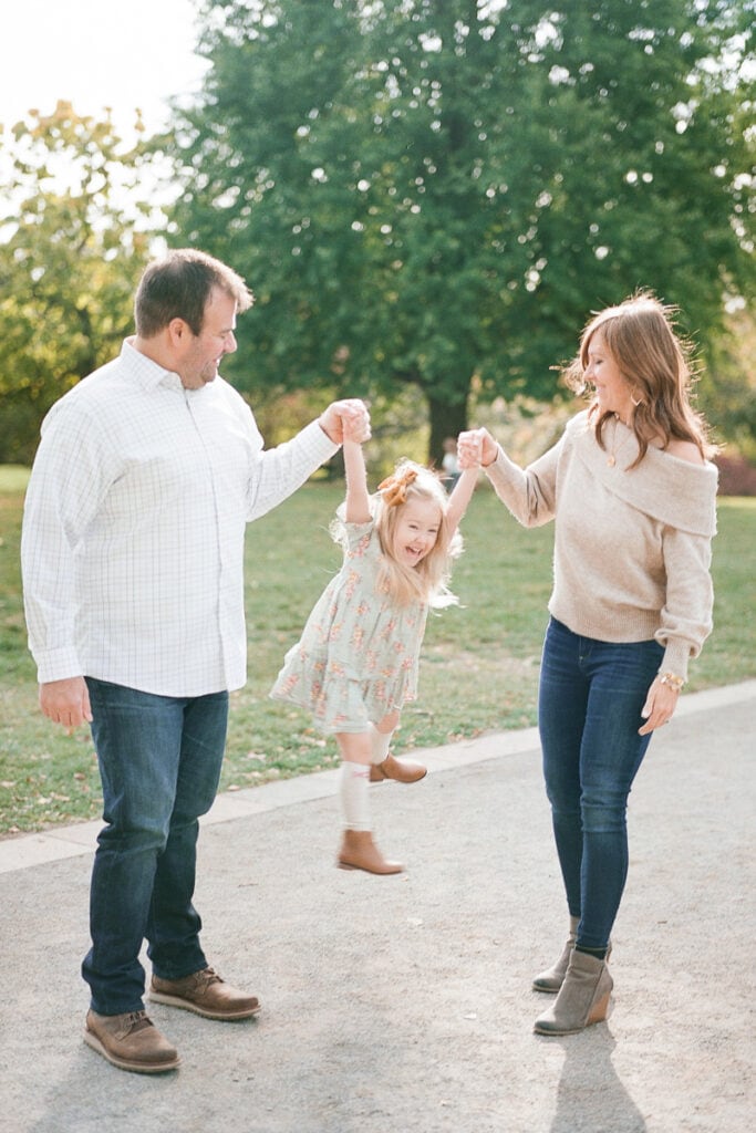 Daughter standing in between her mom and dad holding their hands