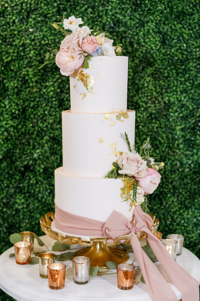 Pink and white wedding cake with gold foil and a pink bow