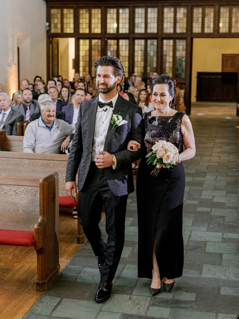 Mother of the groom escorting groom down the aisle