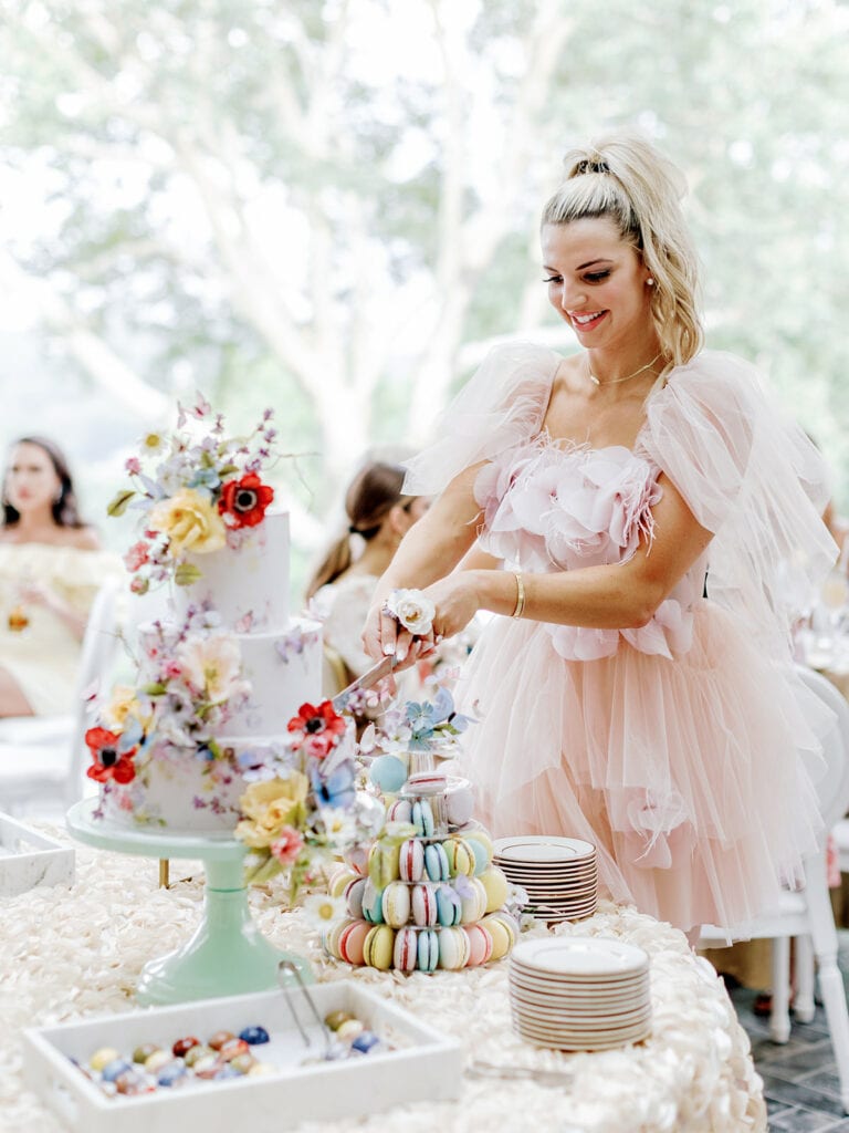 Blogger Sincerely Ryleigh cutting into bridal shower cake from Alex Robba Cake