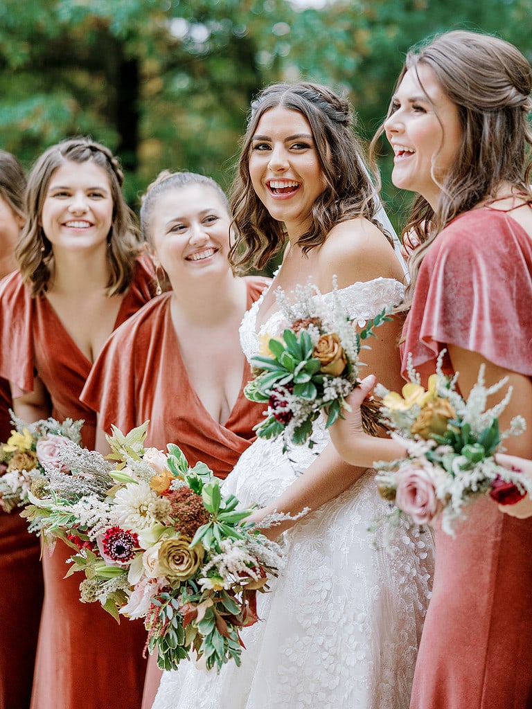 Photo of bride with bridesmaids in terracotta dresses.