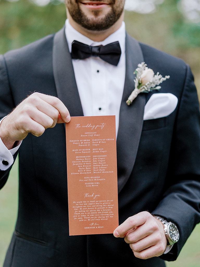 Photo of groom holding a ceremony program for a Pittsburgh wedding.