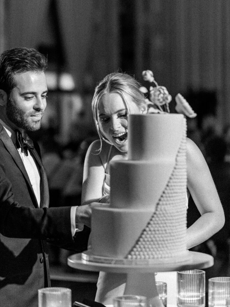 Photo of bride and groom cutting their Pennsylvania wedding cake. Modern Black and White Wedding