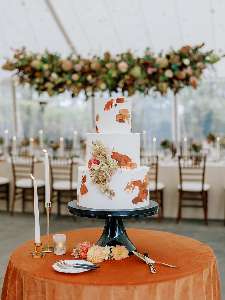 Photo of a painted terracotta cake at a luxury tent wedding reception. Pittsburgh Fall Tented Wedding on a Private Estate