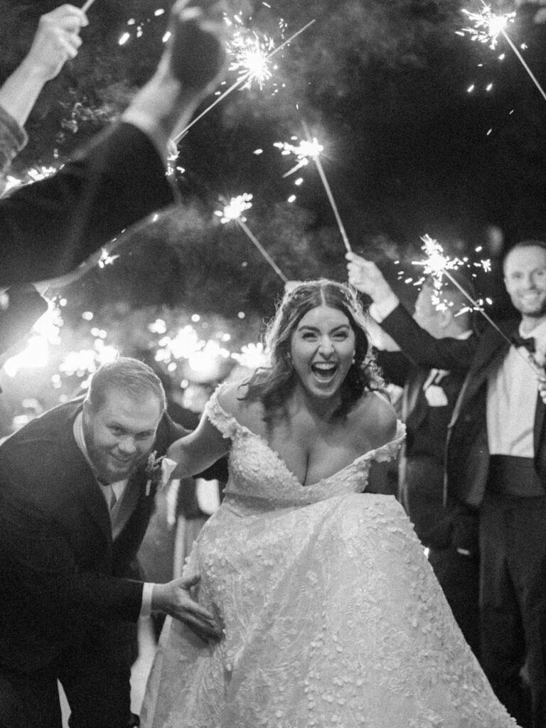 Photo of bride and groom having a sparkler exit at their tented wedding.