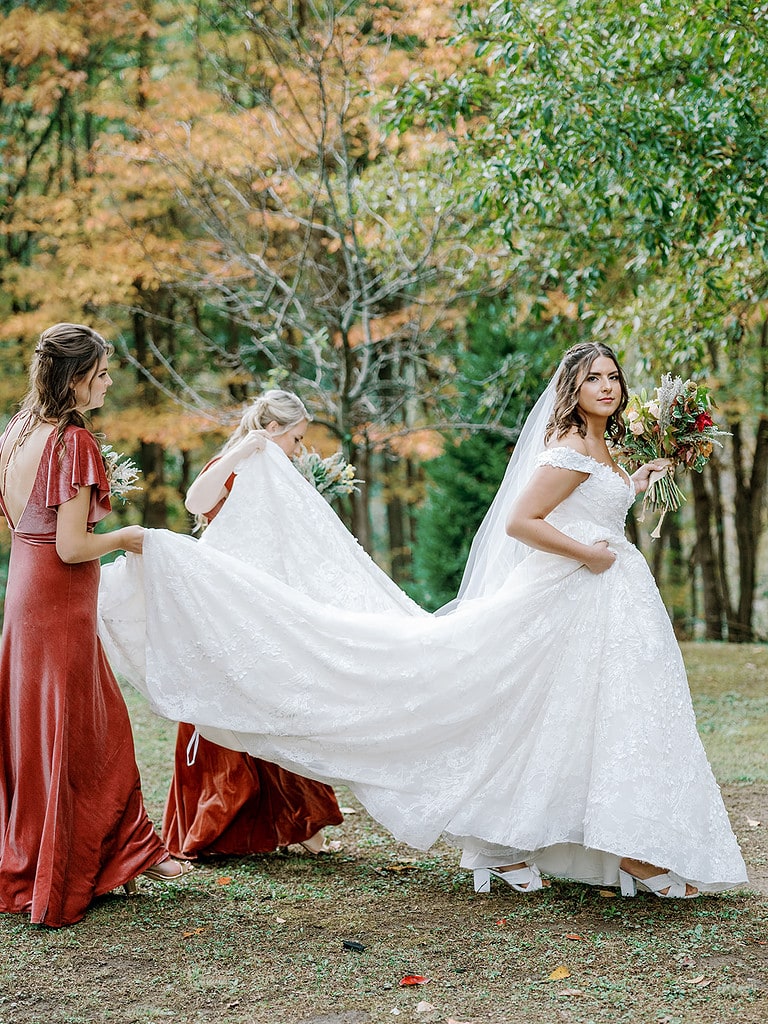 Photo of bridesmaids helping a bride in her wedding dress at a Pittsburgh fall wedding.