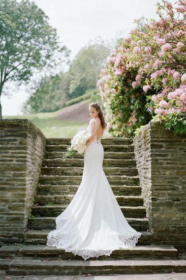 Bride standing on cobblestone staircase holding bouquet