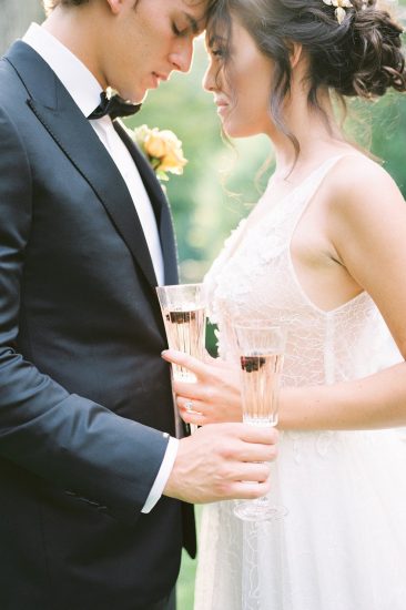 couple holding champagne flutes with black berries