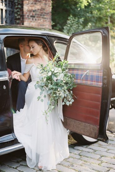 couple sitting in a vintage Chrysler with large white bouquet