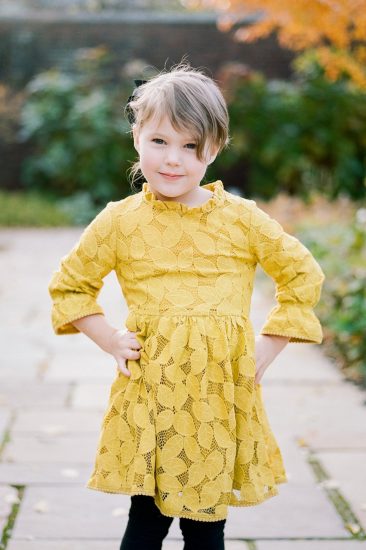 young girl posing for her picture in a yellow lace dress