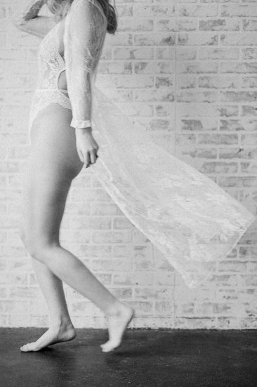 woman walking wearing a white lace robe and lace lingerie black and white photo: Pittsburgh Boudoir Photography