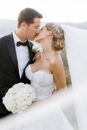Bride and groom kissing with bride's veil in portrait