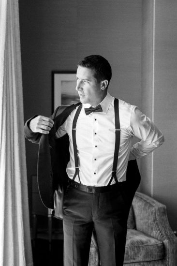 Groom putting on his tuxedo black and white photo