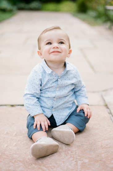 toddler sitting on the ground at the park in blue shirt and pants