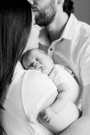 black and white photo of newborn resting on mothers shoulder