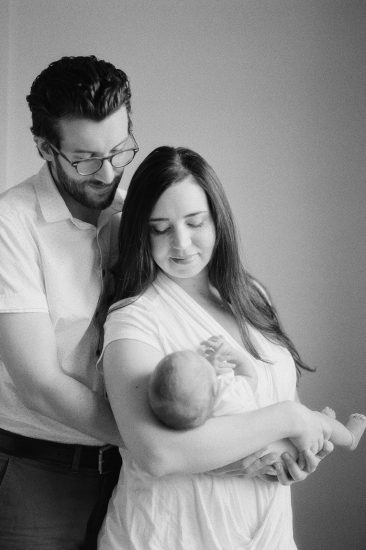 Lifestyle newborn session black and white photo of new parents holding their baby girl