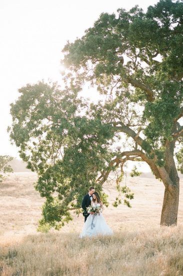 bride and groom standing under a tree at kestrel park