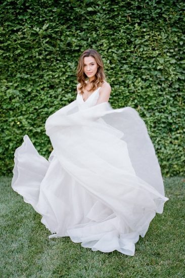 bride wearing a carol hannah bridal gown while dancing in the grass